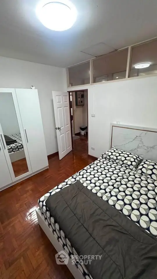 Cozy bedroom with modern decor and wooden flooring, featuring a stylish bed and wardrobe.