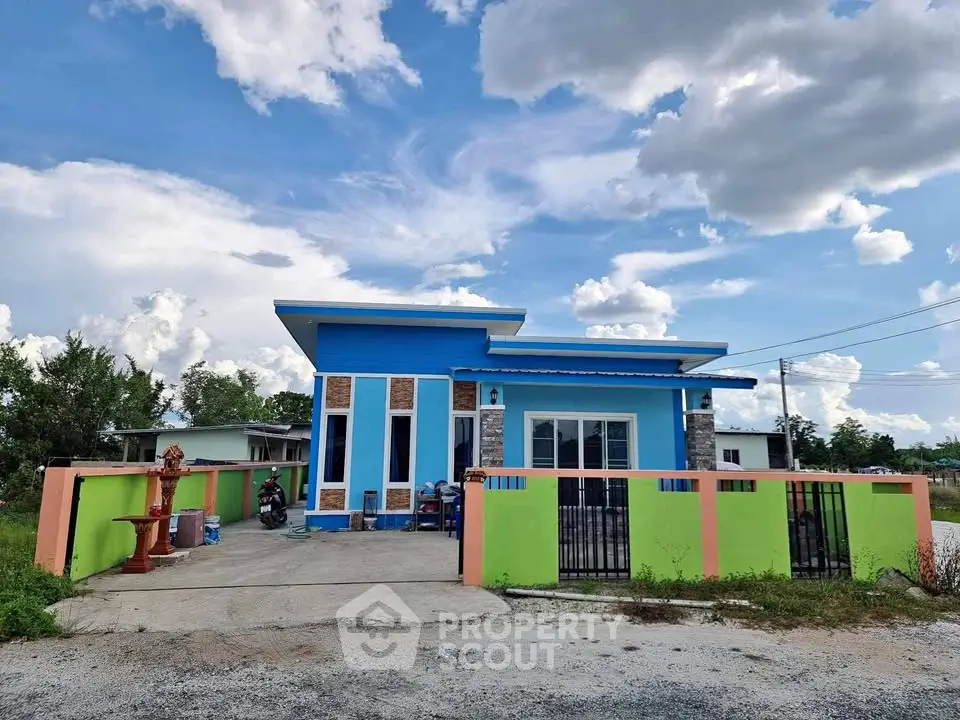 Vibrant single-story home with colorful facade and spacious driveway under a clear sky.