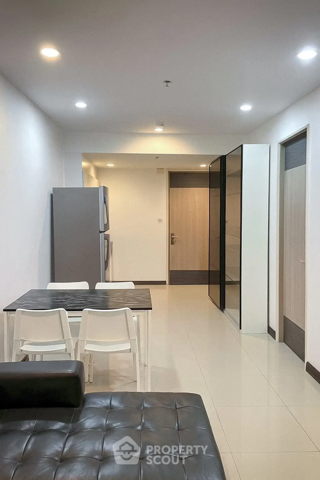 Modern apartment interior with sleek kitchen and dining area, featuring contemporary furniture and bright lighting.