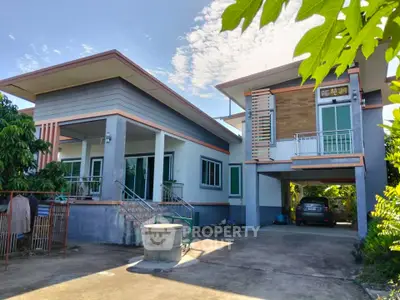 Modern two-story house with carport and lush greenery, showcasing contemporary architecture and spacious driveway.