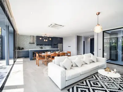 Spacious modern living room with open kitchen, large windows, and stylish decor in luxury home.