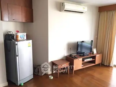 Cozy living room with wooden flooring, TV unit, and air conditioning.