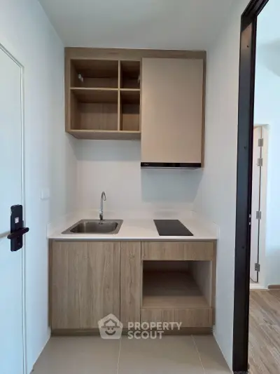 Modern compact kitchen with sleek cabinetry and induction cooktop in a stylish apartment.