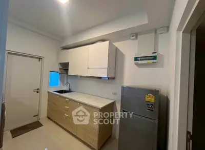 Modern kitchen with sleek cabinetry and stainless steel fridge in compact layout.