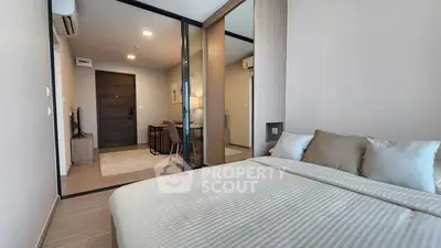 Modern bedroom with cozy bedding and view into stylish living area