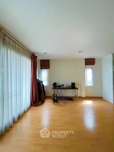 Spacious living room with wooden flooring and large windows for natural light.