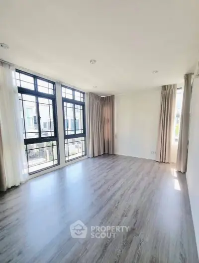 Spacious and bright living room with large windows and elegant flooring