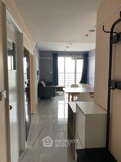 Modern apartment interior with open living and dining area, featuring sleek furniture and large windows.
