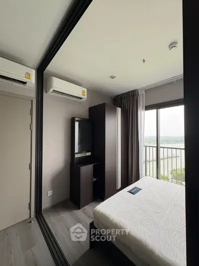 Modern bedroom with balcony view and sleek furnishings in a high-rise apartment.
