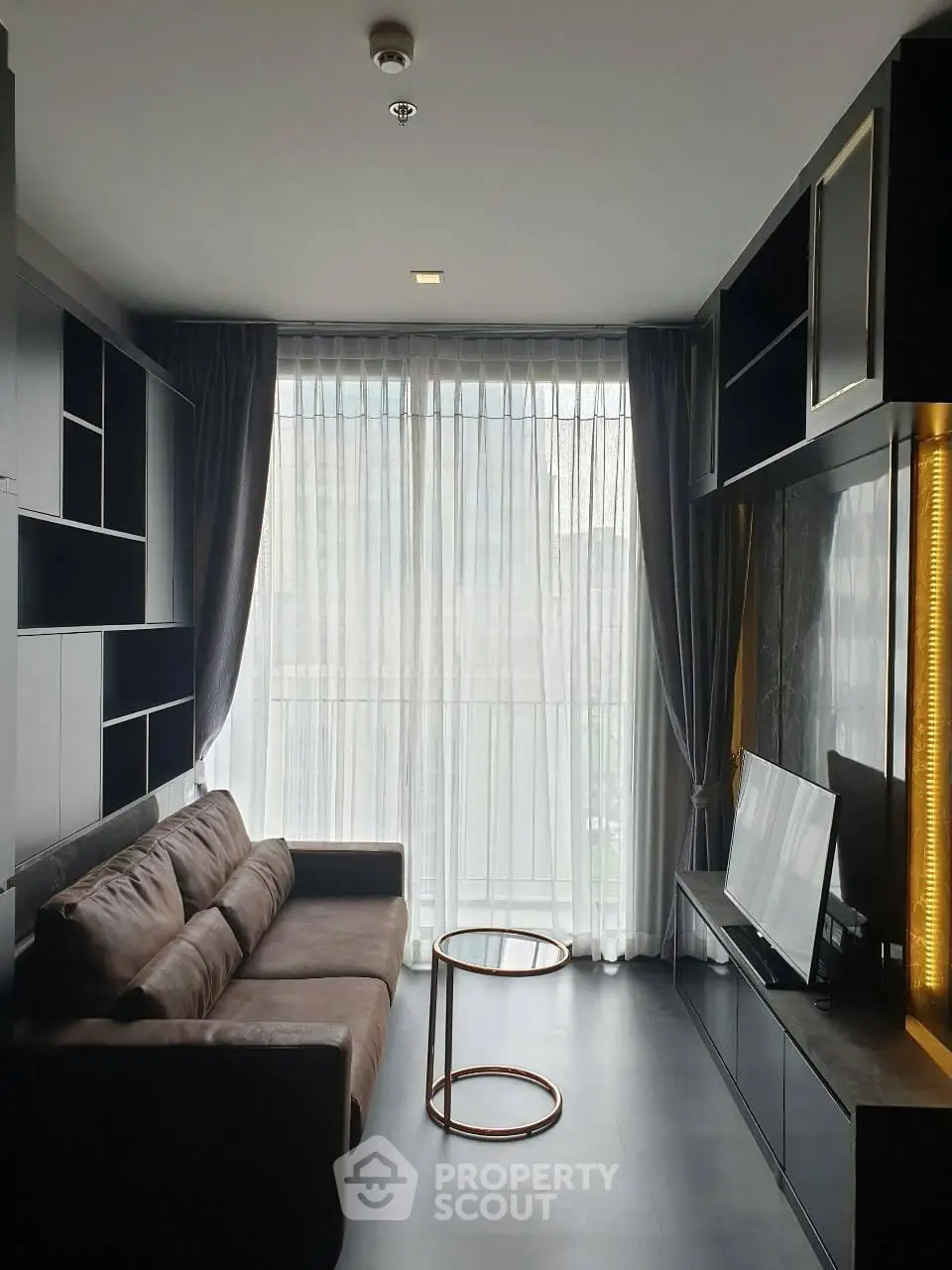 Modern living room with sleek furniture and large window offering natural light