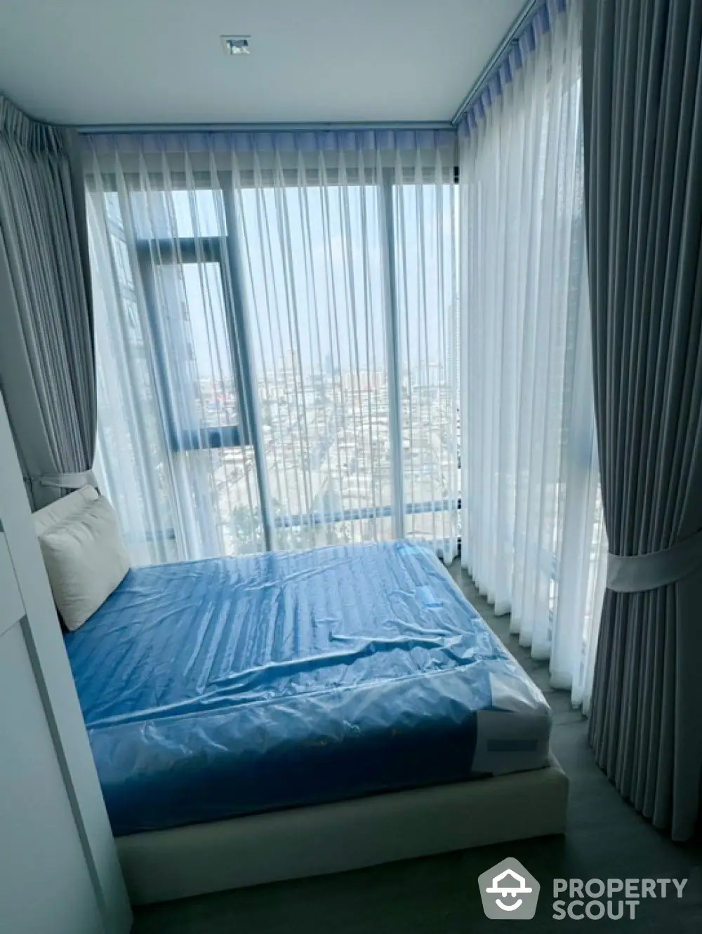 Modern bedroom with floor-to-ceiling windows and city view