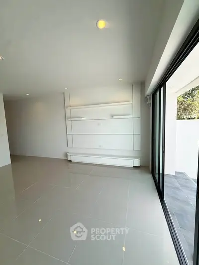 Spacious modern living room with sleek tile flooring and large sliding glass doors.