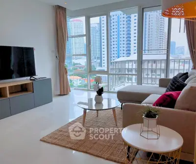 Spacious modern living room with large windows and city view, featuring stylish furniture and decor.
