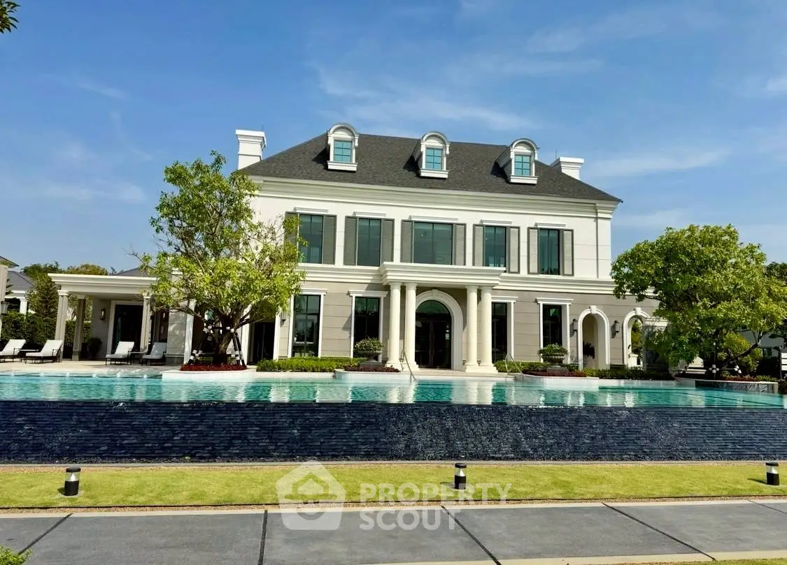 Luxurious mansion with grand pool and elegant architecture under clear blue sky.
