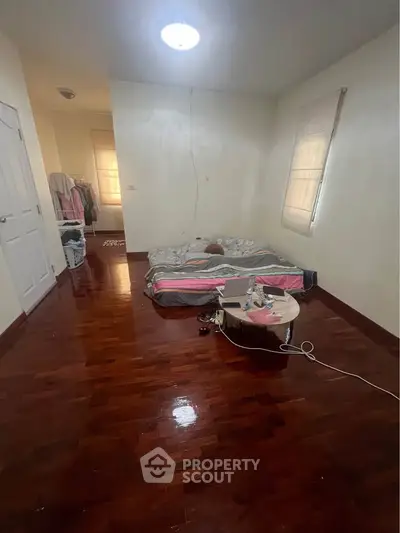Spacious bedroom with wooden flooring and minimalist decor, ideal for cozy living.