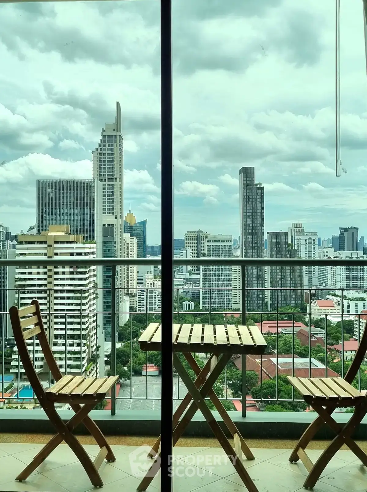 Stunning cityscape view from a high-rise balcony with wooden furniture, perfect for urban living.