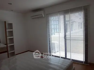 Spacious bedroom with large window and air conditioning in modern apartment.