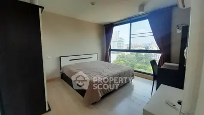 Spacious bedroom with large window offering stunning city views, modern furnishings, and ample natural light.