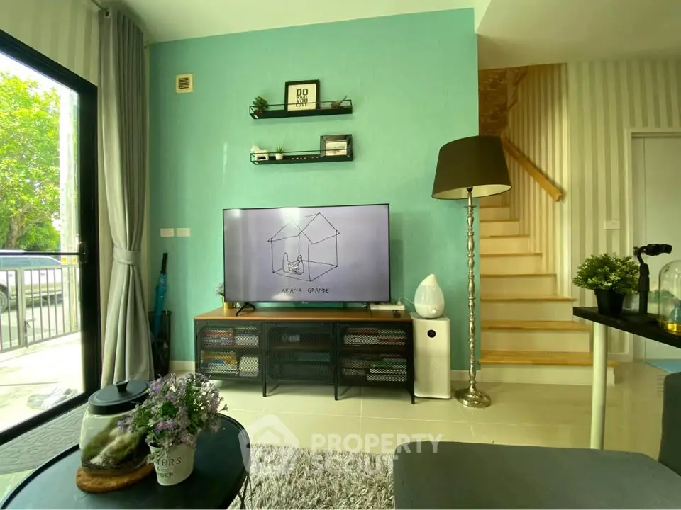 Stylish living room with modern decor and large TV, featuring a cozy ambiance and natural light.