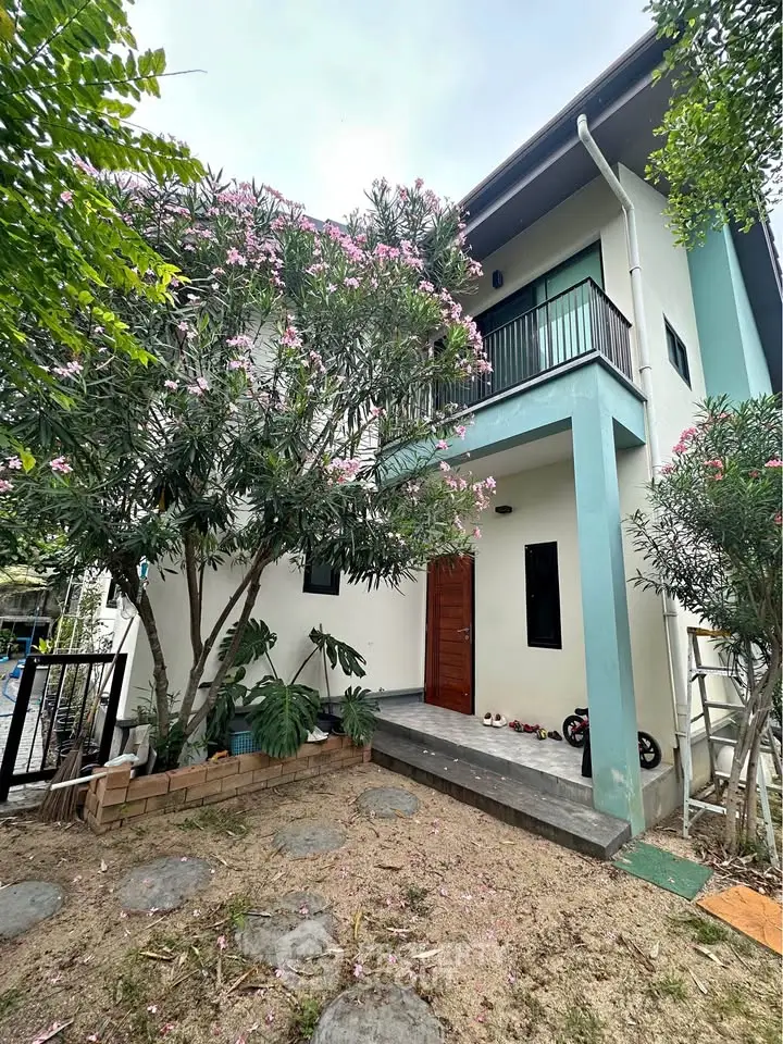 Charming two-story house with lush garden and balcony, perfect for family living.