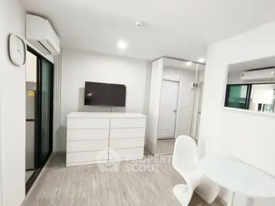 Modern minimalist living room with sleek white furniture and wall-mounted TV