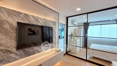 Modern apartment with stylish living room and cozy bedroom separated by glass wall.