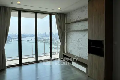 Spacious living room with floor-to-ceiling windows offering stunning city and water views.