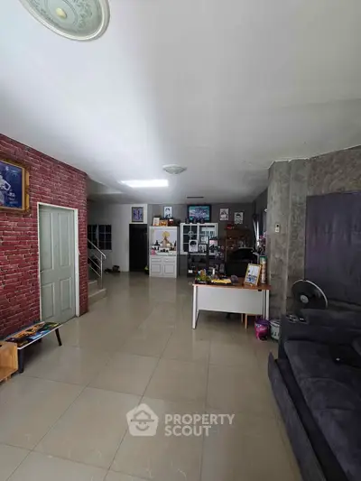 Spacious living room with modern decor and brick accent wall, perfect for family gatherings.