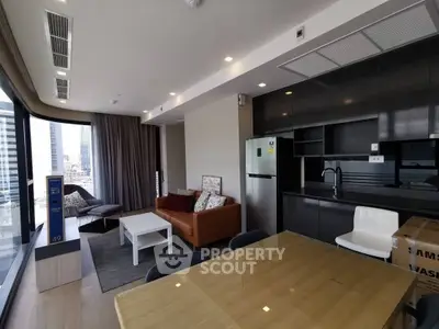 Modern open-layout living room with kitchen, featuring sleek furniture and city view.