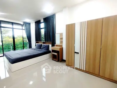 Spacious modern bedroom with large windows and sleek wooden furniture.