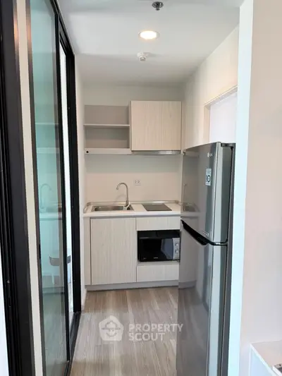 Modern compact kitchen with sleek appliances and stylish cabinetry in a contemporary apartment.