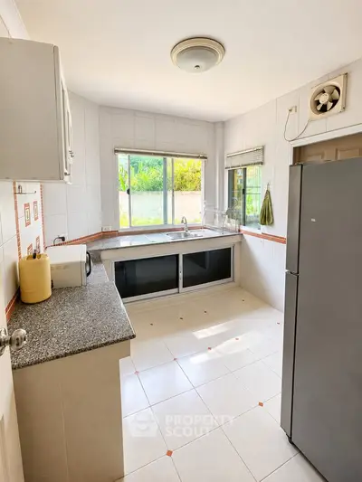 Bright kitchen with large window, modern appliances, and ample counter space in a stylish home.