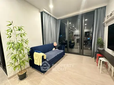 Modern living room with blue sofa and large windows offering a city view.