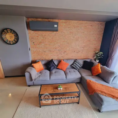 Stylish living room with exposed brick wall and modern gray sectional sofa.