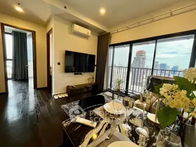 Modern living room with city view, stylish decor, and open layout in high-rise apartment.