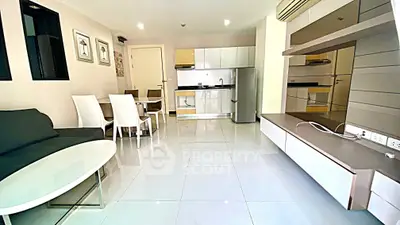 Modern open-plan living room with sleek kitchen and dining area, featuring glossy tile flooring and contemporary furniture.