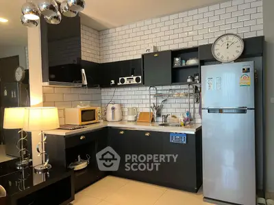 Modern kitchen with sleek black cabinets and stainless steel appliances, featuring a stylish open layout.