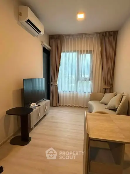Cozy living room with modern decor, featuring a TV, air conditioning, and elegant curtains.