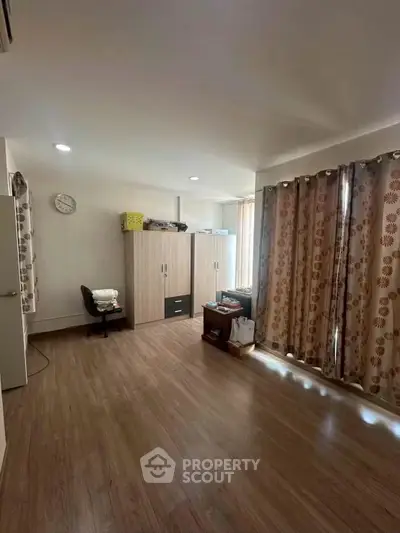 Spacious bedroom with wooden flooring and ample natural light, featuring modern wardrobe and cozy workspace.