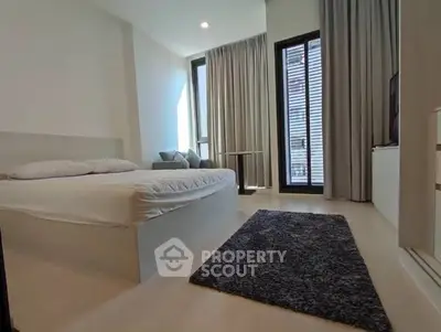 Modern bedroom with large windows and cozy decor in a stylish apartment.