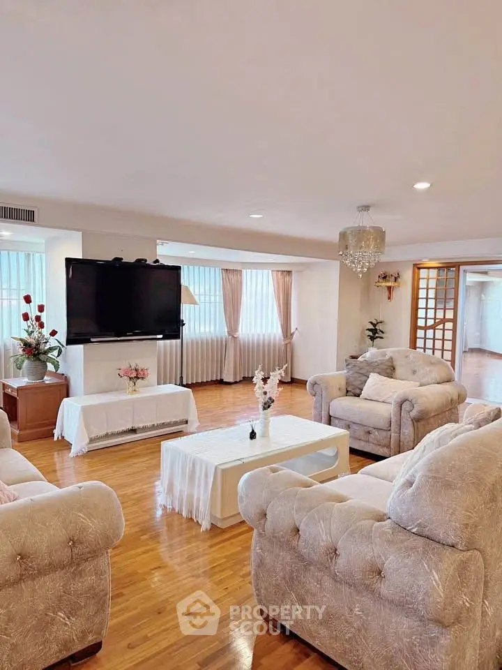 Elegant living room with plush sofas, large TV, and natural light from wide windows.