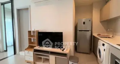 Modern apartment interior with TV, fridge, and washing machine in open layout.