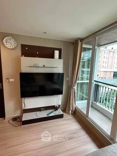 Modern living room with large TV and balcony view in urban apartment