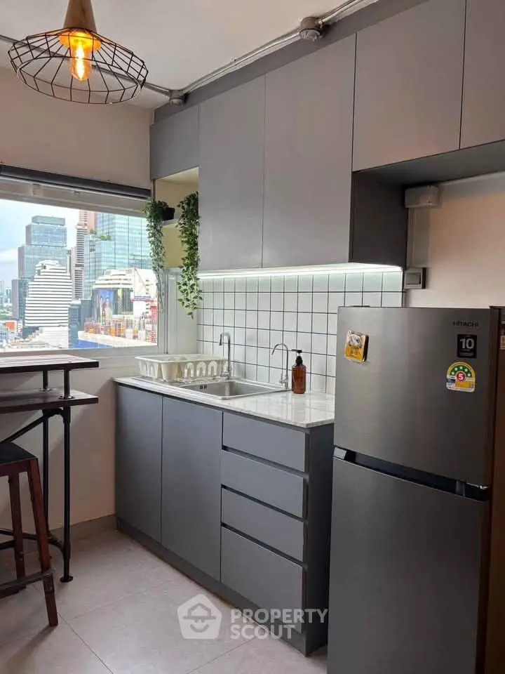 Modern kitchen with sleek cabinetry and city view, featuring a compact dining area and stainless steel appliances.