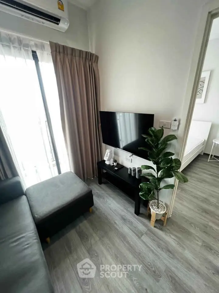 Modern living room with sleek decor and natural light, featuring a cozy sofa and flat-screen TV.