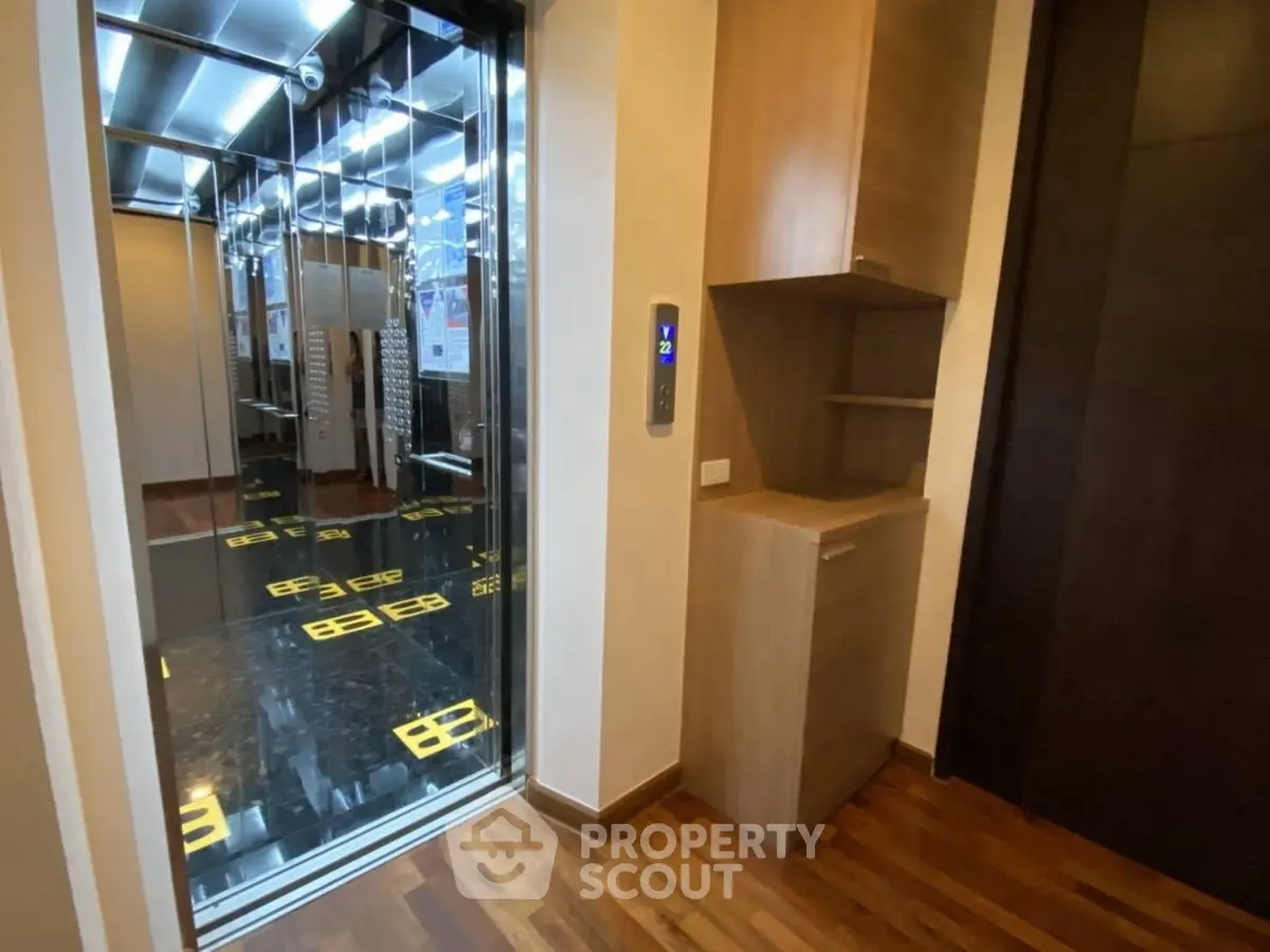 Modern elevator with sleek interior and wooden flooring in a residential building.