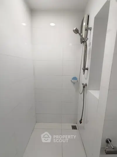 Minimalist white tiled bathroom with modern shower fixtures