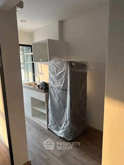Modern compact kitchen with new fridge and sleek cabinetry in a cozy apartment setting.