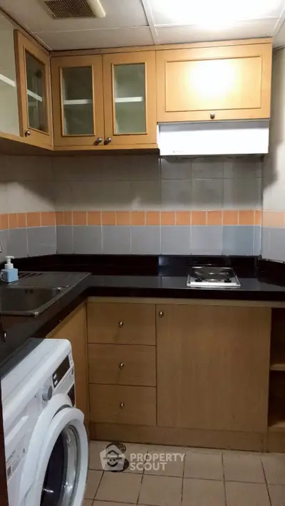 Compact kitchen with wooden cabinets and built-in washing machine