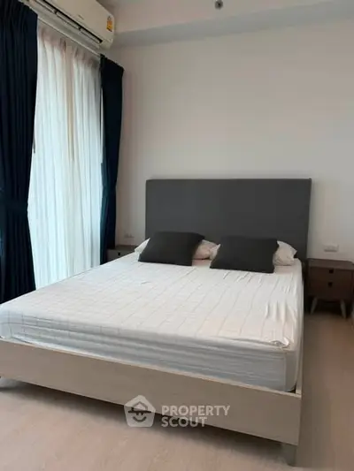 Modern bedroom with stylish bed and natural light from large window.